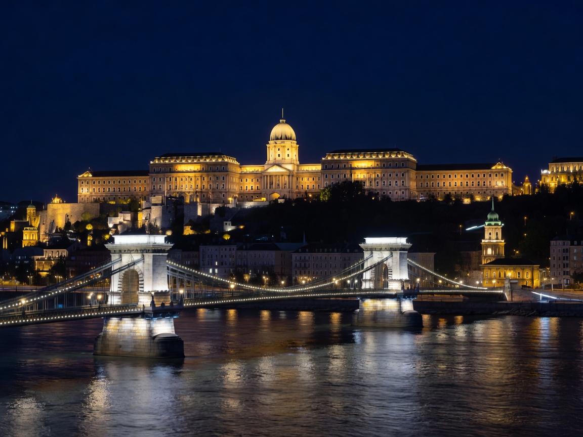 Buda Castle glowing above Chain Bridge spanning the dark Danube river at Budapest